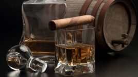 cigar sitting on top of a glass of whiskey