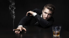 editorial photo of man with a cigar and a glass of whiskey